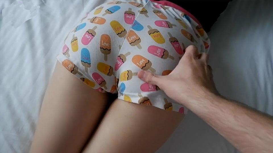 Блондинка в цветных шортах лежит на кровати и принимает в щель член оператора